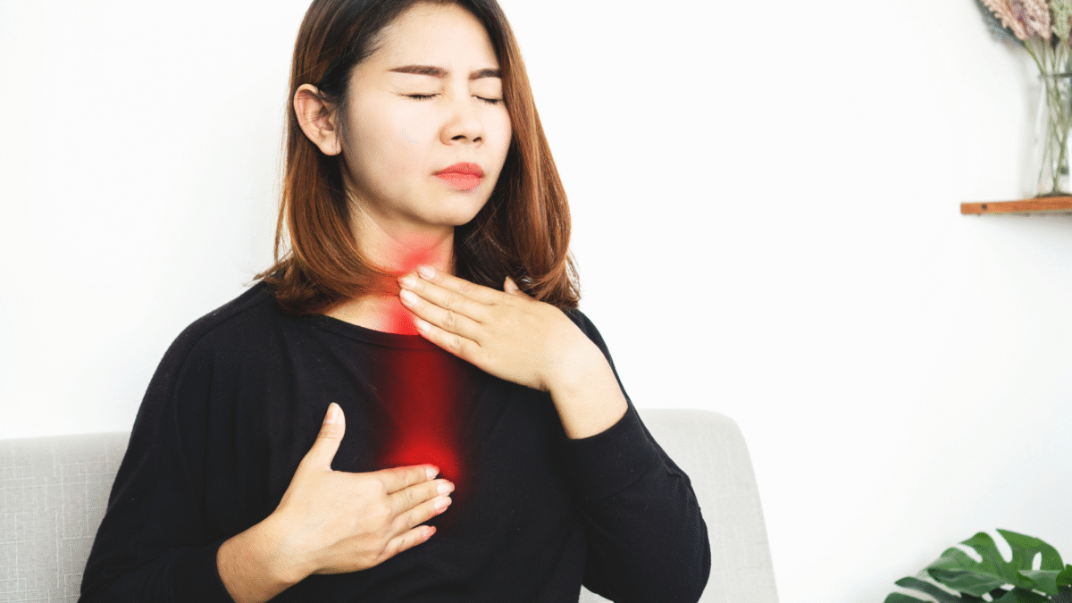 Woman clutching her chest in discomfort, showing signs of acid reflux or heartburn.